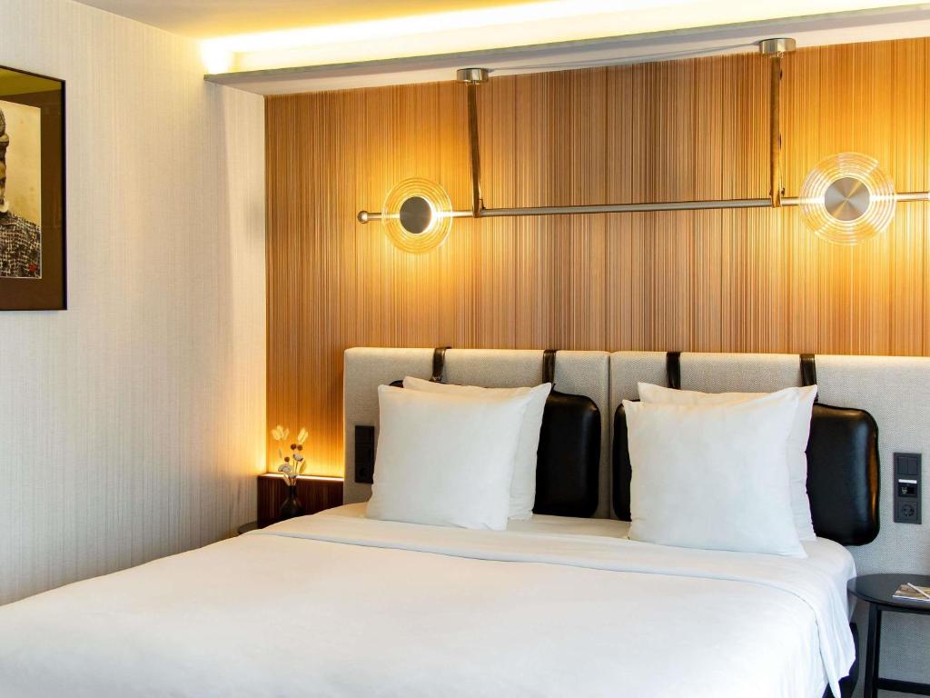a bedroom with a large bed with white pillows at MUZE Hotel Dusseldorf - Handwritten Collection in Düsseldorf