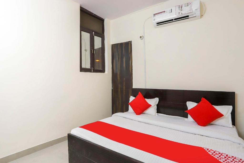 a bedroom with a bed with red and white pillows at Hotel O Royal Residenc in Indirapuram