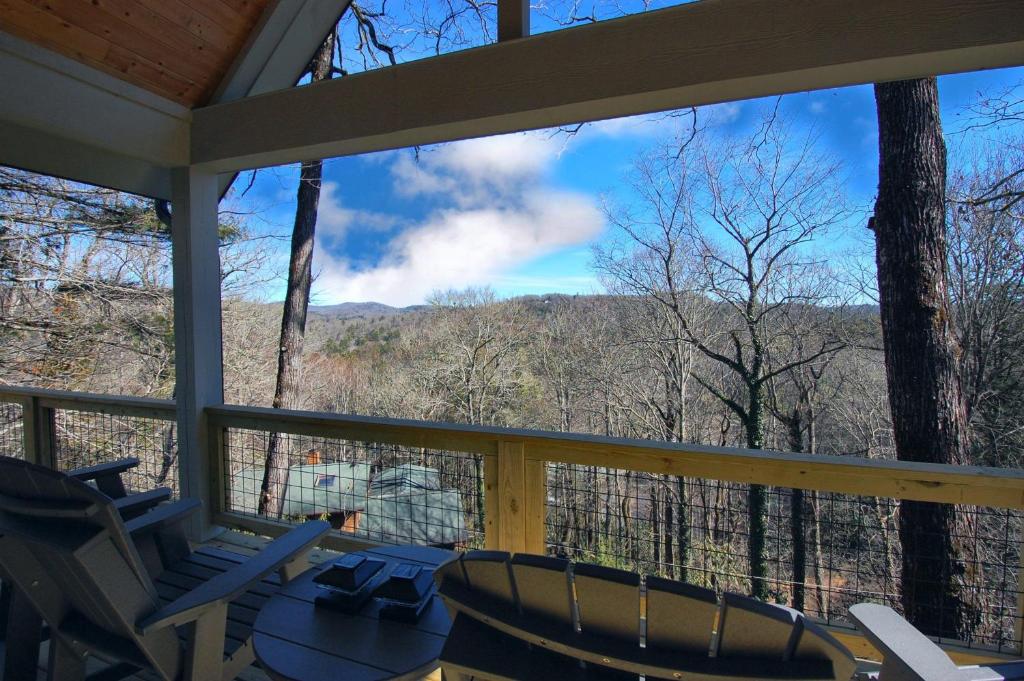 a screened in porch with chairs and a view of the mountains at The Owlery in Highlands