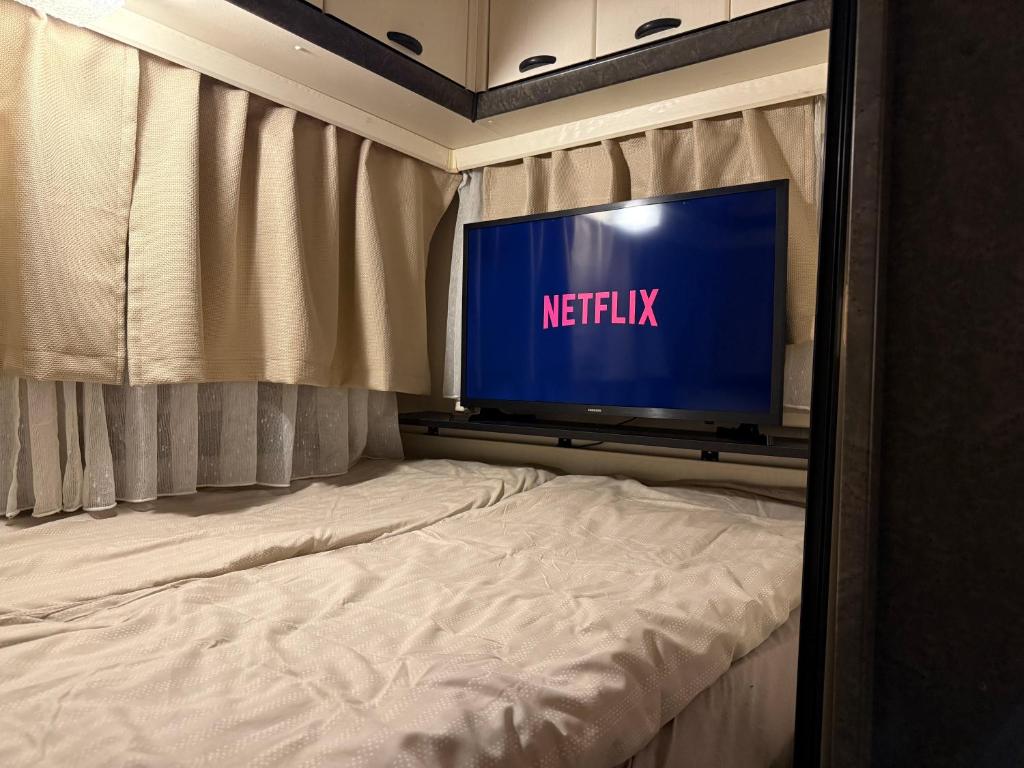 TV en la parte superior de una cama en una habitación en Fully Equipped Caravan 1, en Gentofte