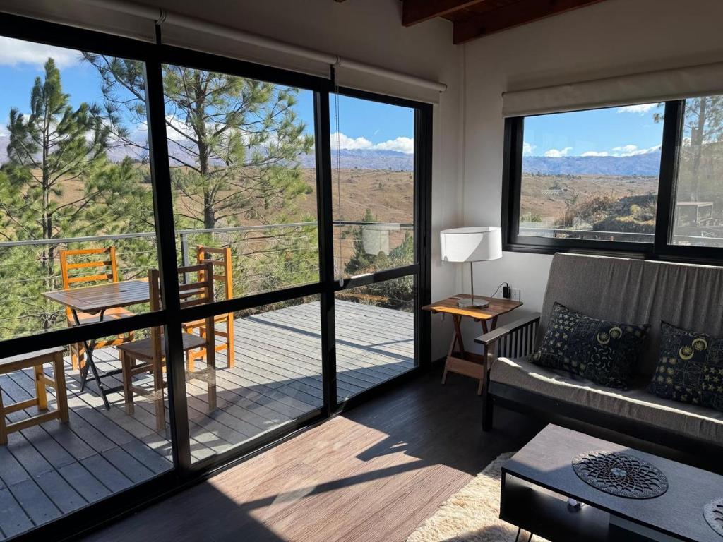 een woonkamer met een bank en een balkon met uitzicht bij La Colina de Villa Yacanto in Villa Yacanto