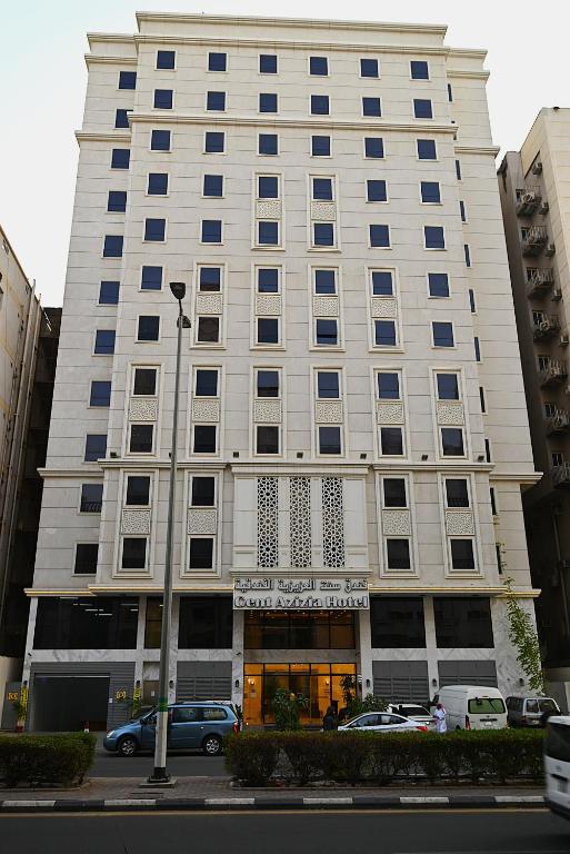 a tall white building with cars parked in front of it at Cent Al Azizia Hotel Makkah in Mecca