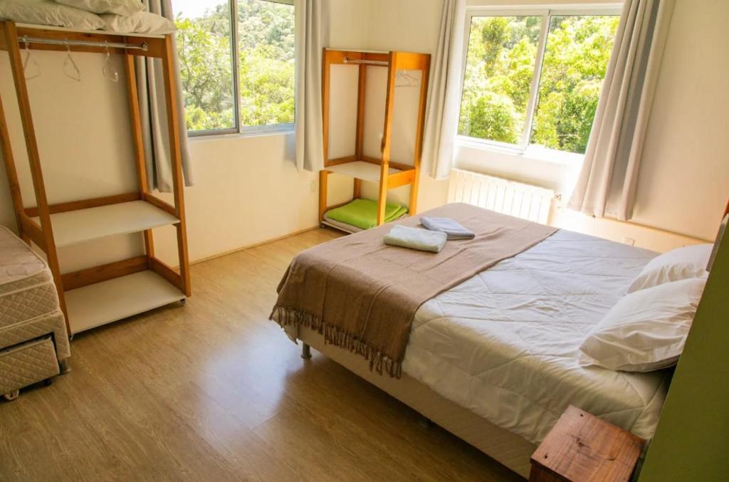 ein Schlafzimmer mit einem Bett und zwei Fenstern in der Unterkunft Casa do Reiki - Terapias & Aconchego na Natureza in Rancho Queimado