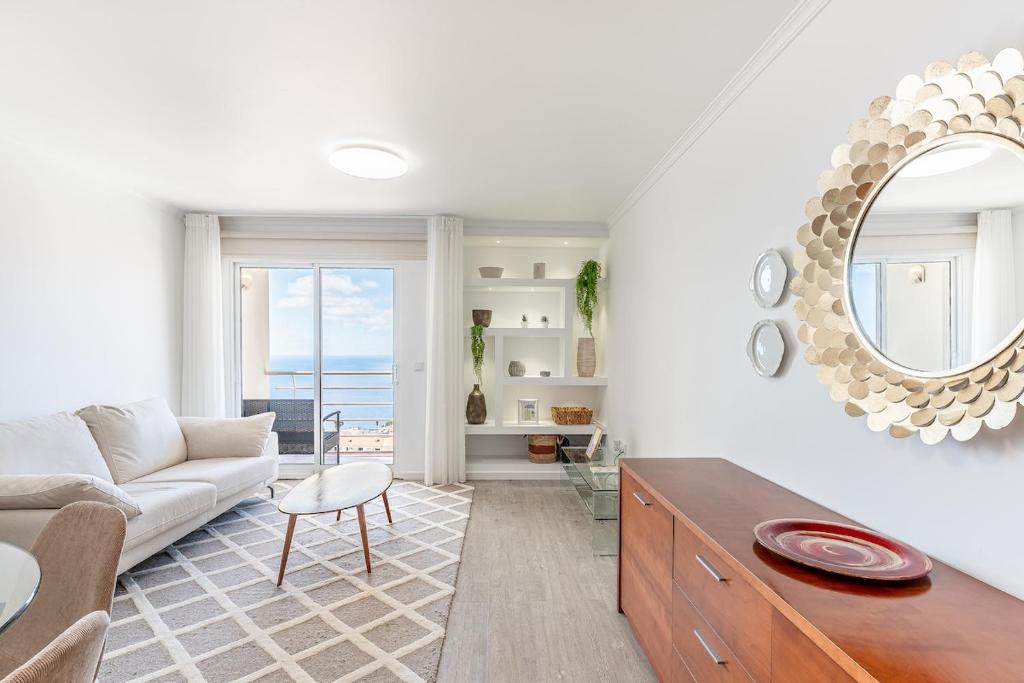 a living room with a couch and a mirror at Topaz Scape Garajau Madeira by GRM in Caniço