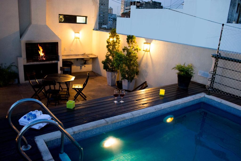 a swimming pool with a wooden deck and a fireplace at Piccaluga Apartments in Buenos Aires