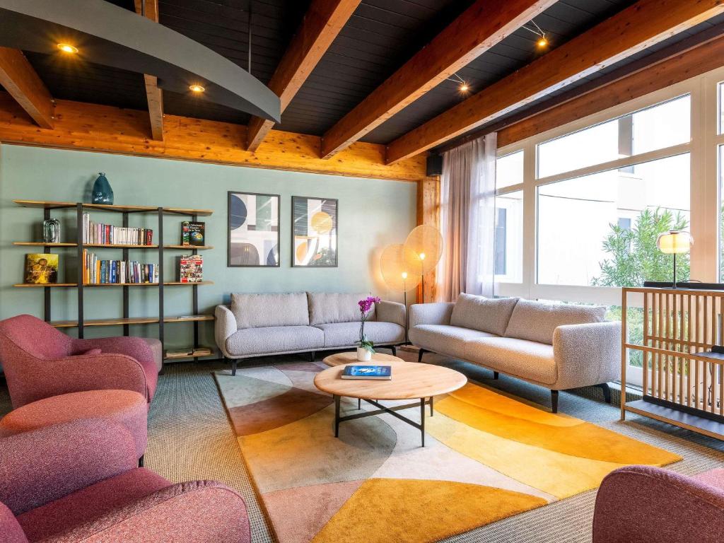 een woonkamer met banken en een tafel bij Novotel Grenoble Nord Voreppe in Voreppe