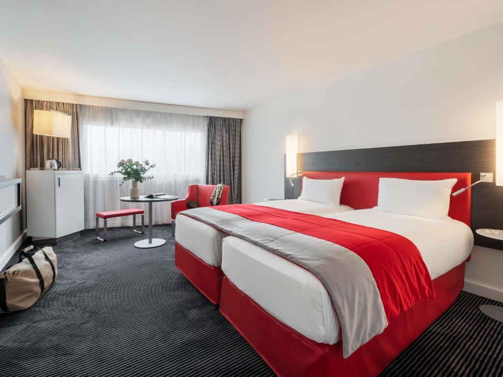 a hotel room with a large bed and a table at Mercure Paris CDG Airport & Convention in Roissy-en-France