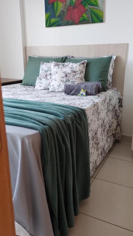 Cama con sábanas y almohadas verdes y blancas en Sua casa longe de casa, en Samambaia