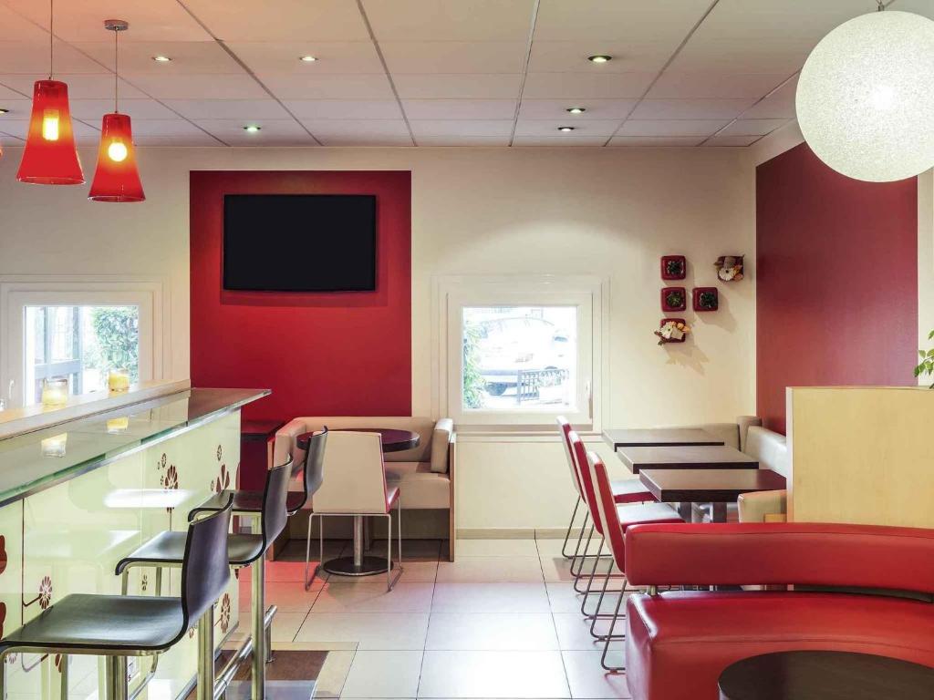 un restaurant avec des murs rouges, des tables et des chaises dans l'établissement ibis Epinay sur Seine - Gennevilliers, à Épinay-sur-Seine