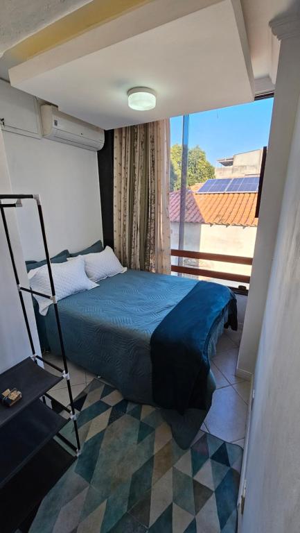 Un dormitorio con una cama y un balcón. en Quarto Plutão - banheiro privativo e ar condicionado, en Duque de Caxias