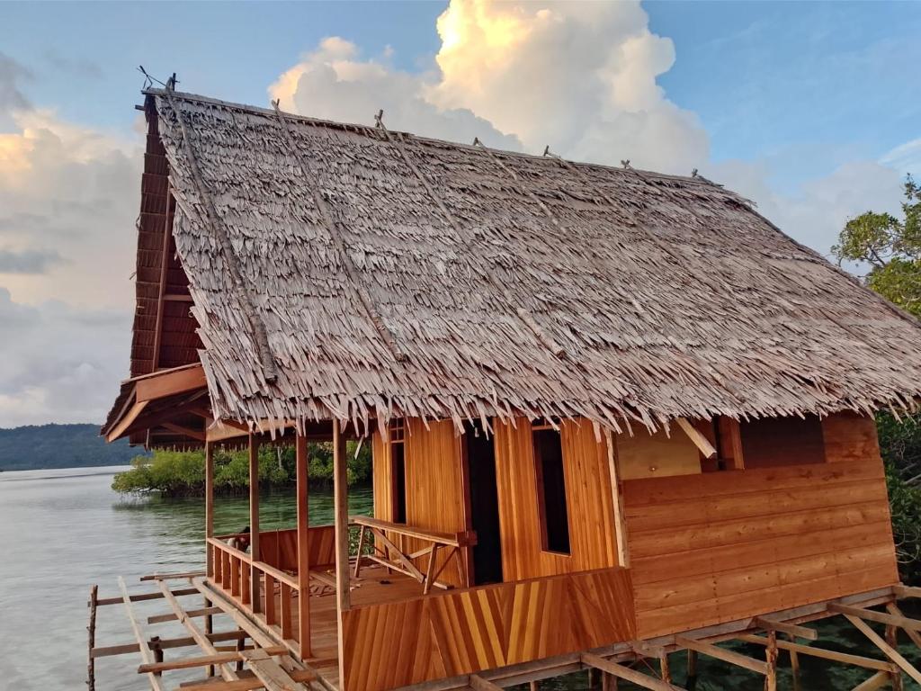 a house with a thatched roof on the water at The Driftwood House 