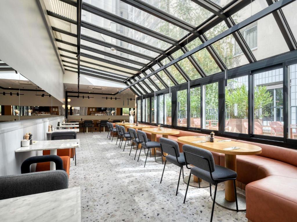 a restaurant with tables and chairs and windows at Mercure Paris 15 Porte de Versailles in Paris