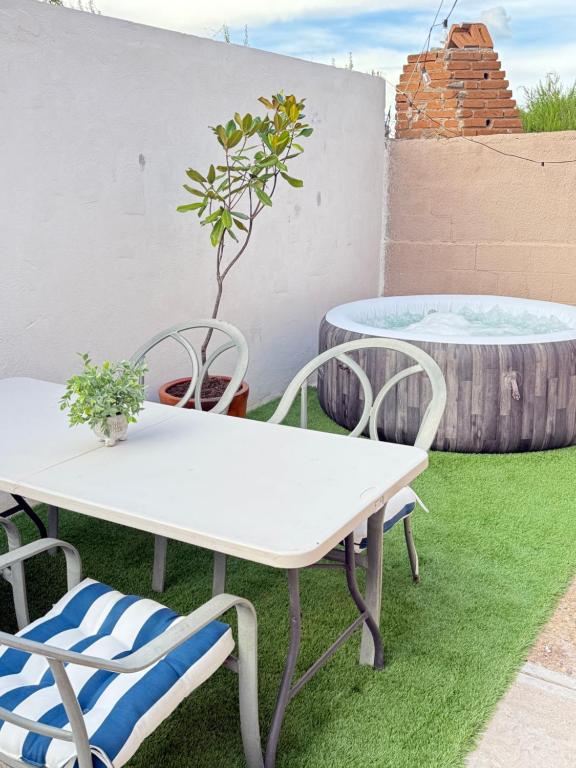 a white table and chairs on a lawn with a plant at Casa con Jacuzzi cerca de Distrito 1 in Chihuahua