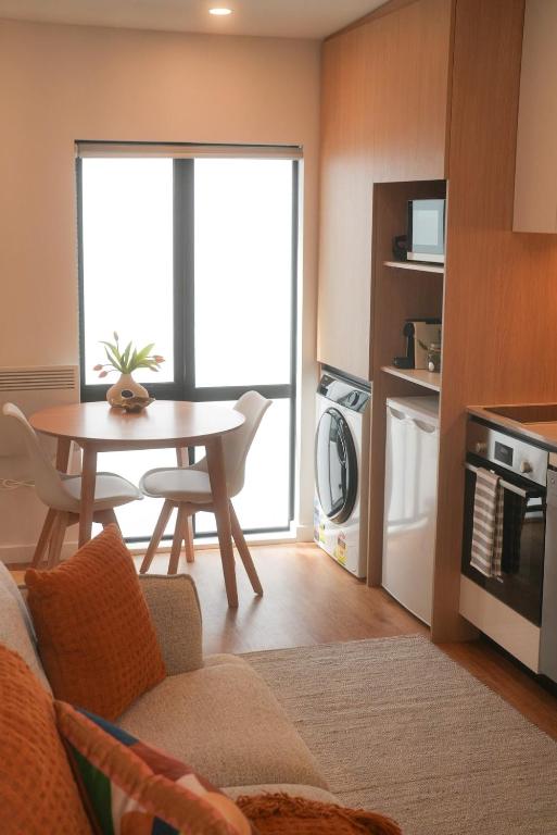 a living room with a table and a kitchen at The Urban Nest in Wellington