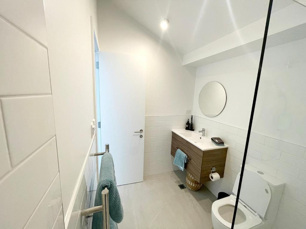 Un baño blanco con inodoro y lavabo. en Villa in the heart of Matakana, en Matakana
