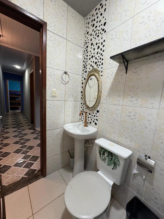 a bathroom with a toilet and a sink and a mirror at Casa Luke Paraty in Paraty