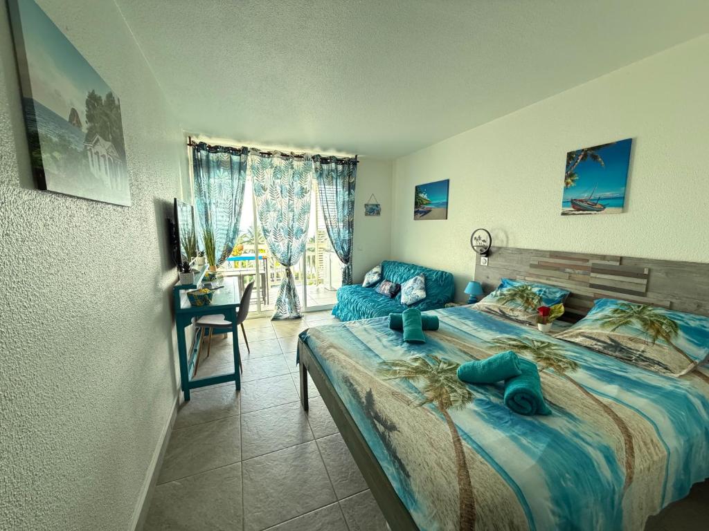 a bedroom with a bed and a desk and a window at Studio Ti Saphir in Le Diamant