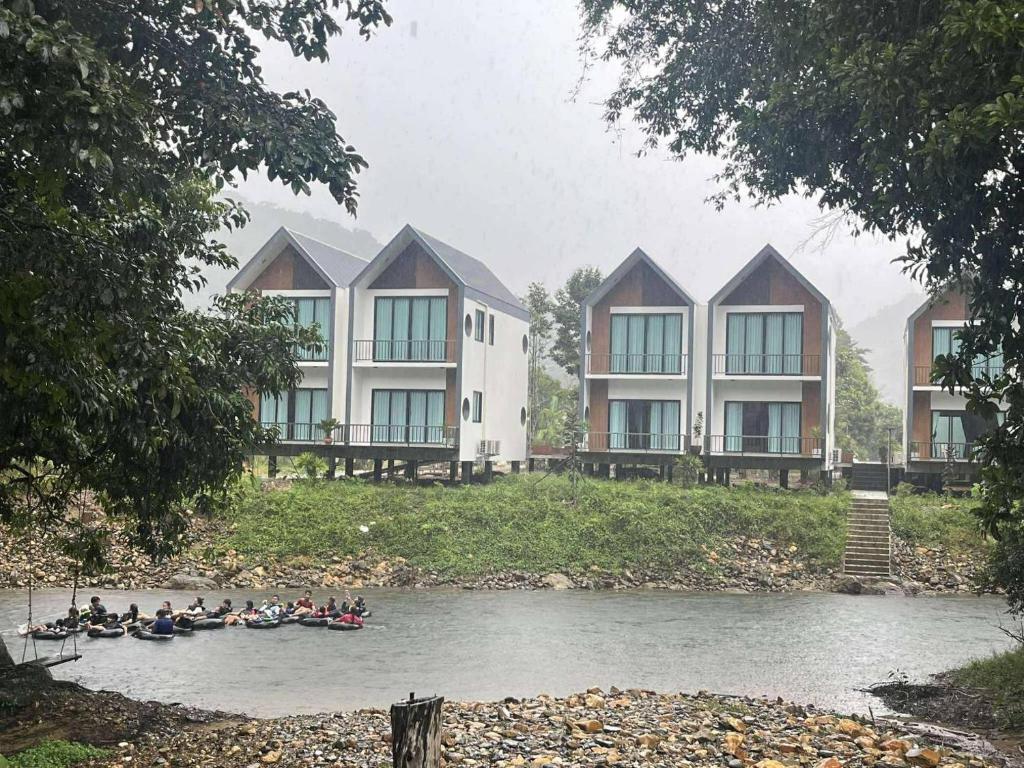 a group of people in canoes on a river with buildings at The River khaosok in Khao Sok