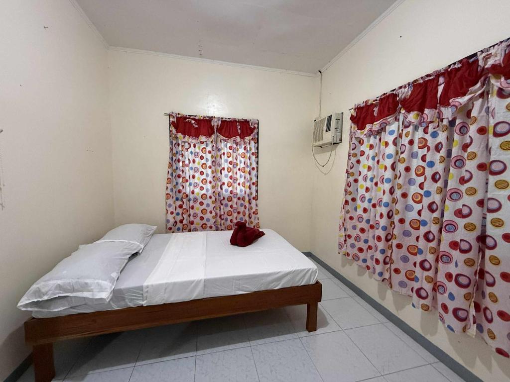 a small bedroom with a bed and curtains at Casa Fleur in Cangalwang