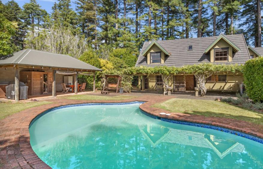 a house with a swimming pool in front of a house at Hawkings Lodge in Kerikeri