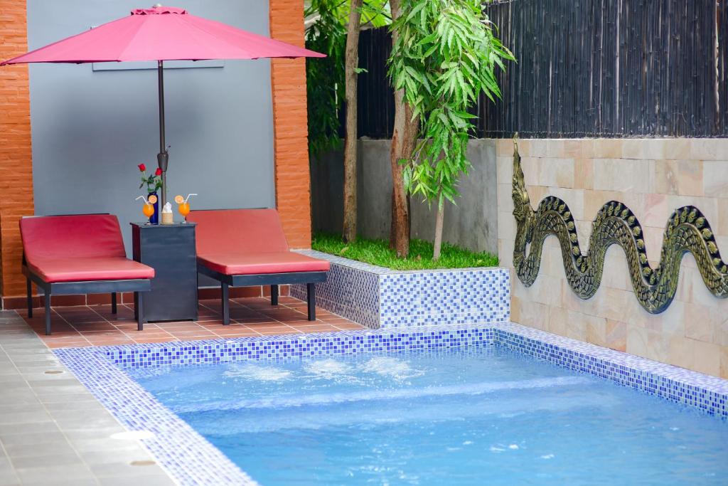 a swimming pool with two chairs and an umbrella at Nina Angkor Residences in Siem Reap