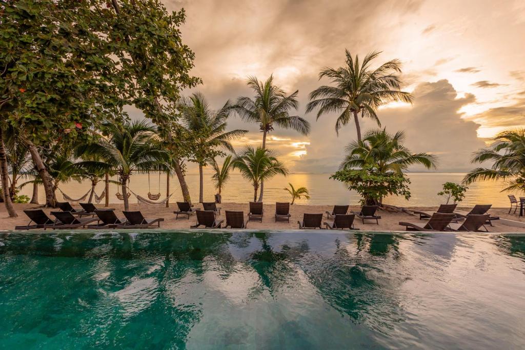 a swimming pool with chairs and palm trees and the ocean at Samaraya Wellness Resort in Amphoe Koh Samui