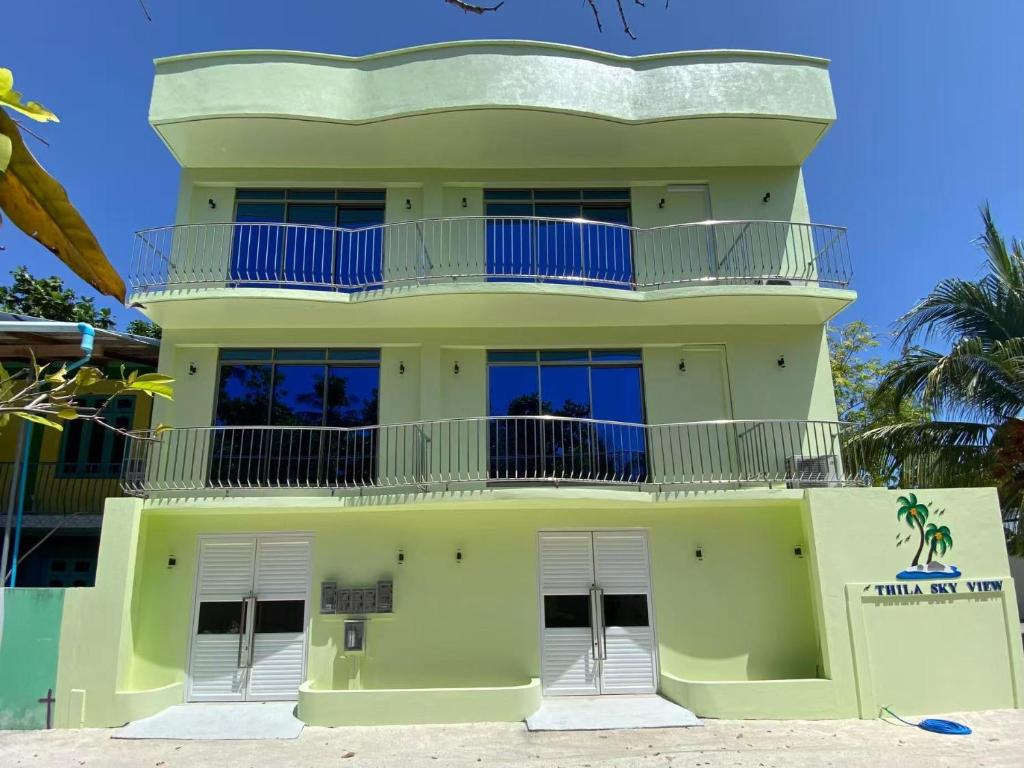 a yellow building with blue balconies on a beach at Thila Sky View in Thoddoo