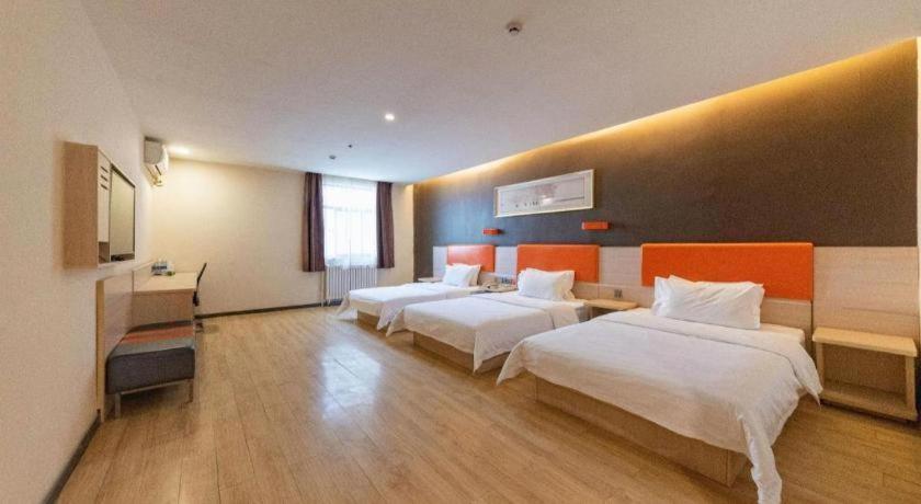 a hotel room with three beds and a desk at 7 Days Premium Jinan Gaoxin Qu Wanda Plaza in Jinan