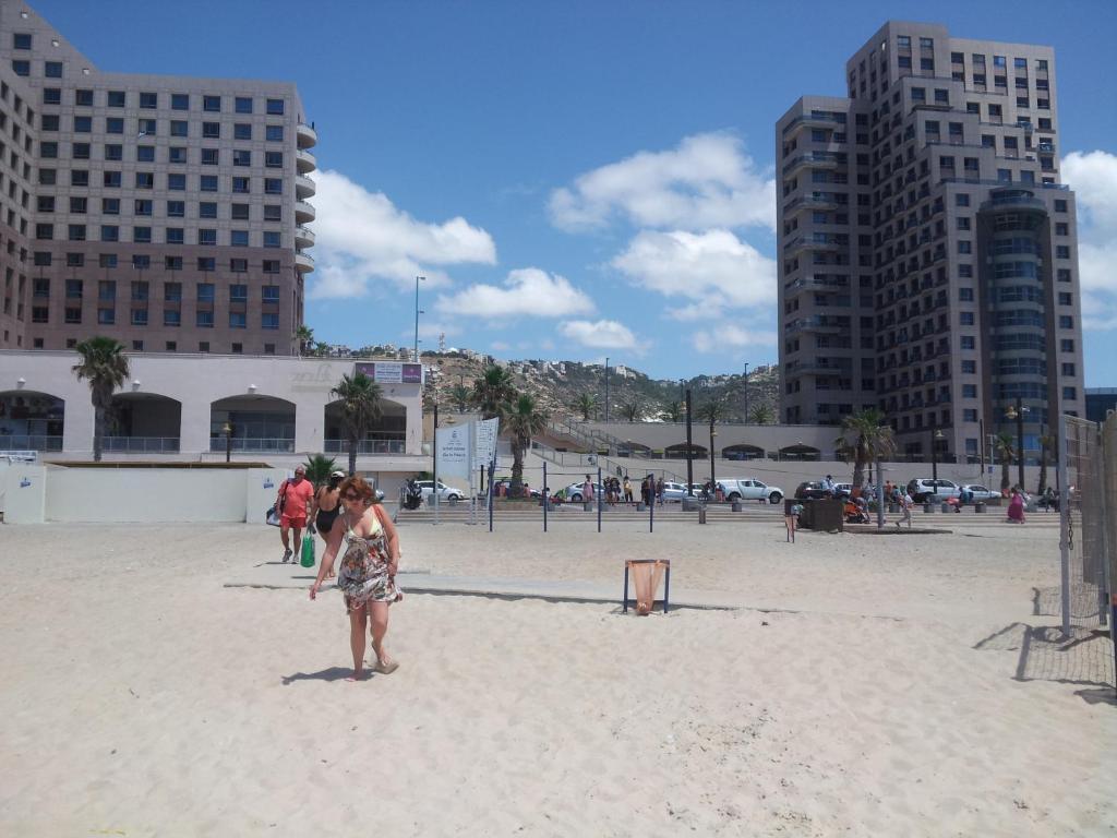 un grupo de personas de pie en una playa con edificios en beach Apartments, en Haifa