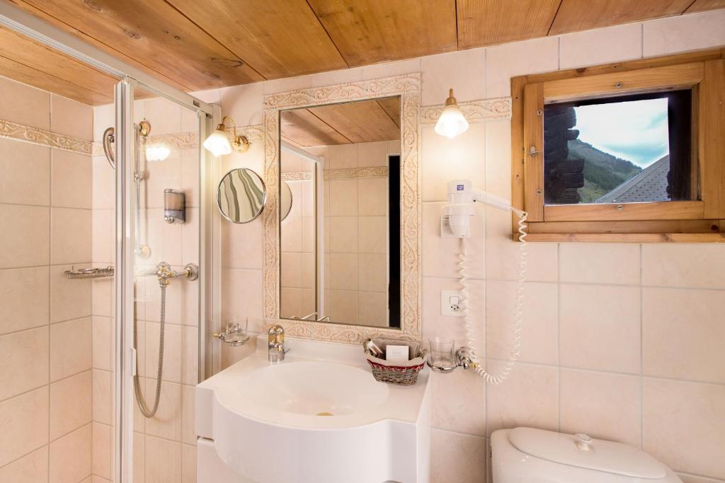 a bathroom with a sink and a toilet and a mirror at Hotel Romantica in Zermatt