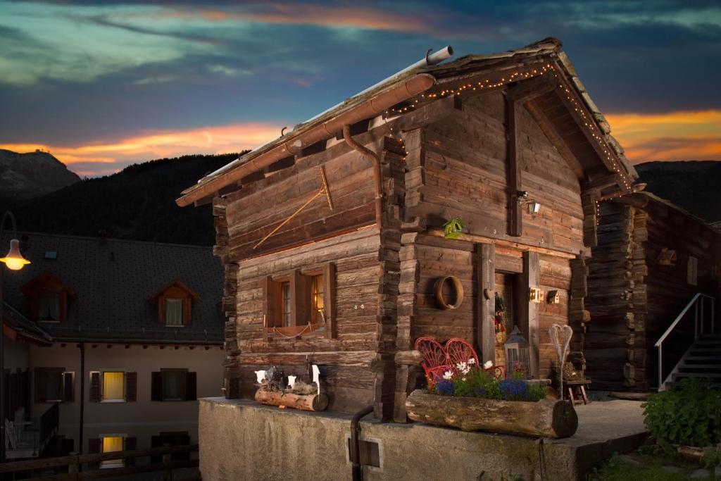 a small wooden house with a sunset in the background at Hotel Romantica in Zermatt