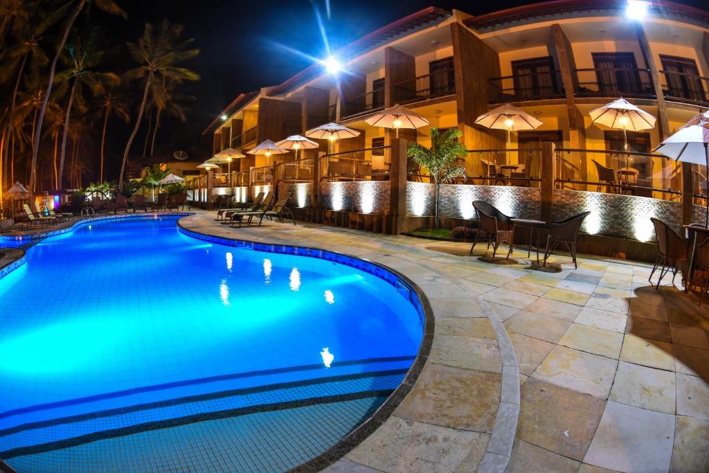 a swimming pool in front of a hotel at night at Genus Beach Hotel in Lagoinha