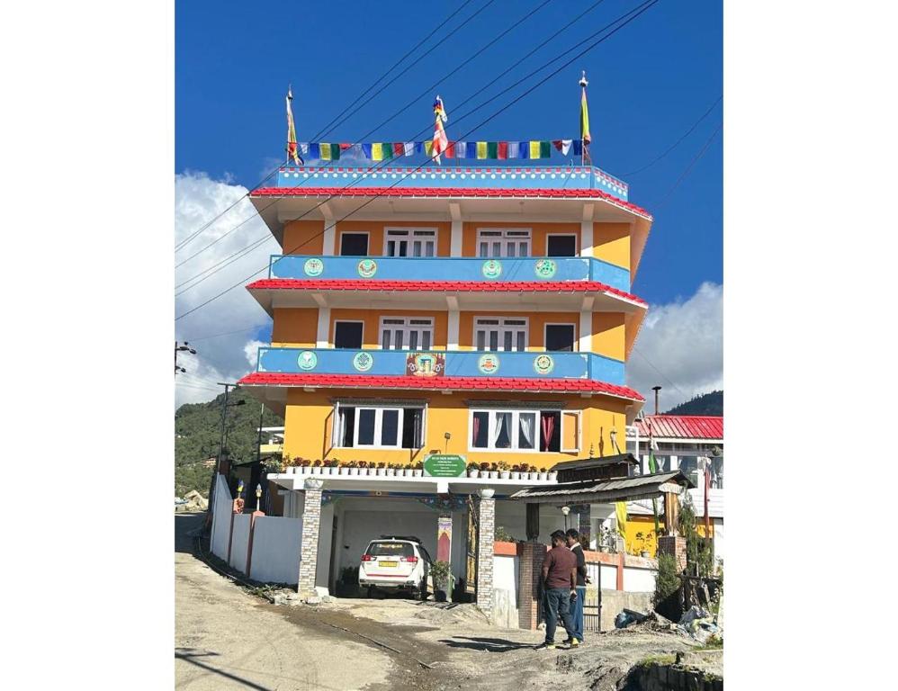 a man standing in front of a yellow building at Ana SonamTsomu, Tawang in Tawang