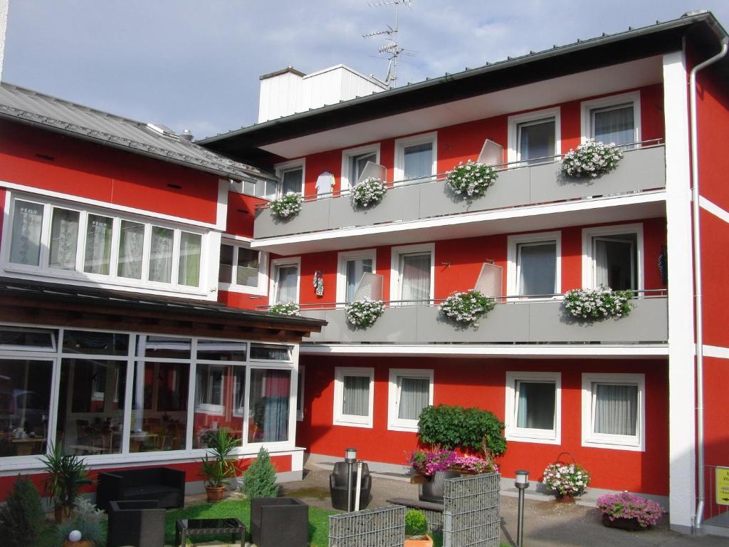 a red building with potted plants on the balconies at Haus Hildegard in Bad Füssing