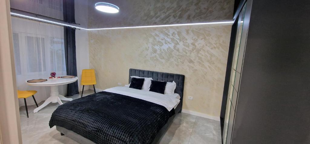 ein Schlafzimmer mit einem Bett und einem Tisch mit einem Fenster in der Unterkunft Studio Premium in Târgu Jiu