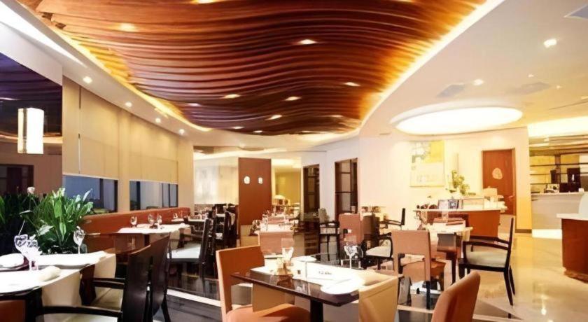 a dining room with tables and chairs in a restaurant at Ramada by Wyndham Wujiaochang Shanghai in Shanghai