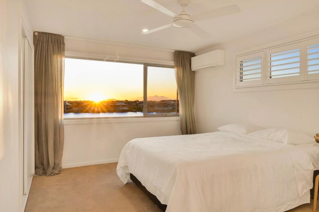 Un dormitorio con una cama y una ventana con la puesta de sol. en Waterfront-Bay View, en Port Macquarie