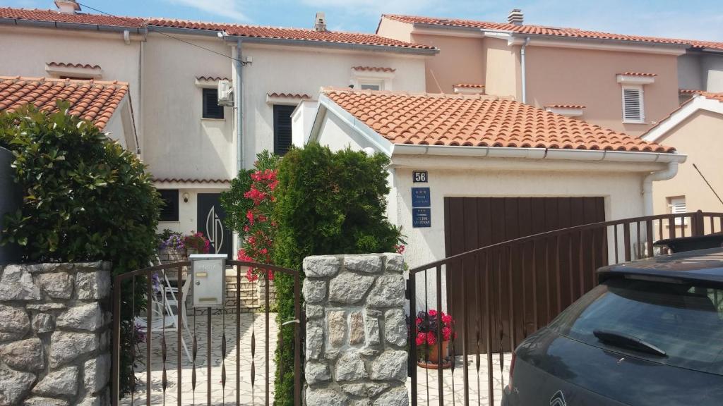 a house with a gate and a car parked in front at Apartment Melina in Omišalj