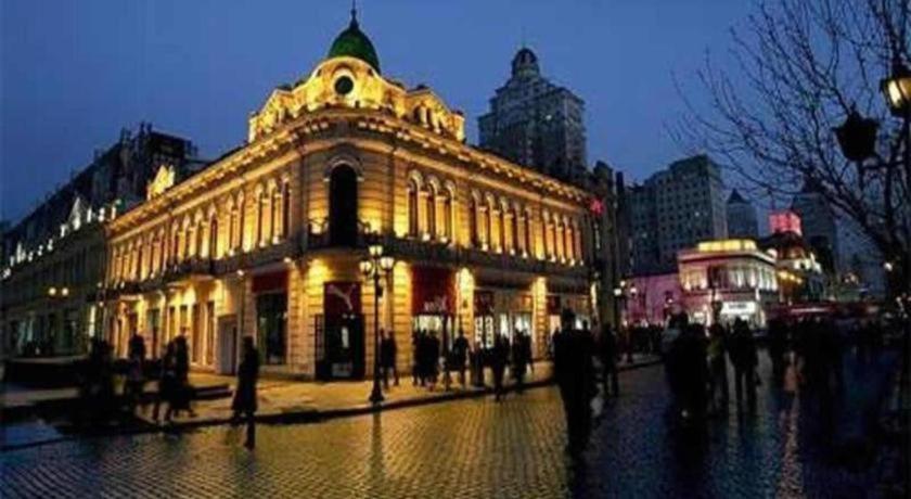 un bâtiment éclairé dans une ville la nuit dans l'établissement 7 Days Inn Harbin West Railway Station, à Harbin