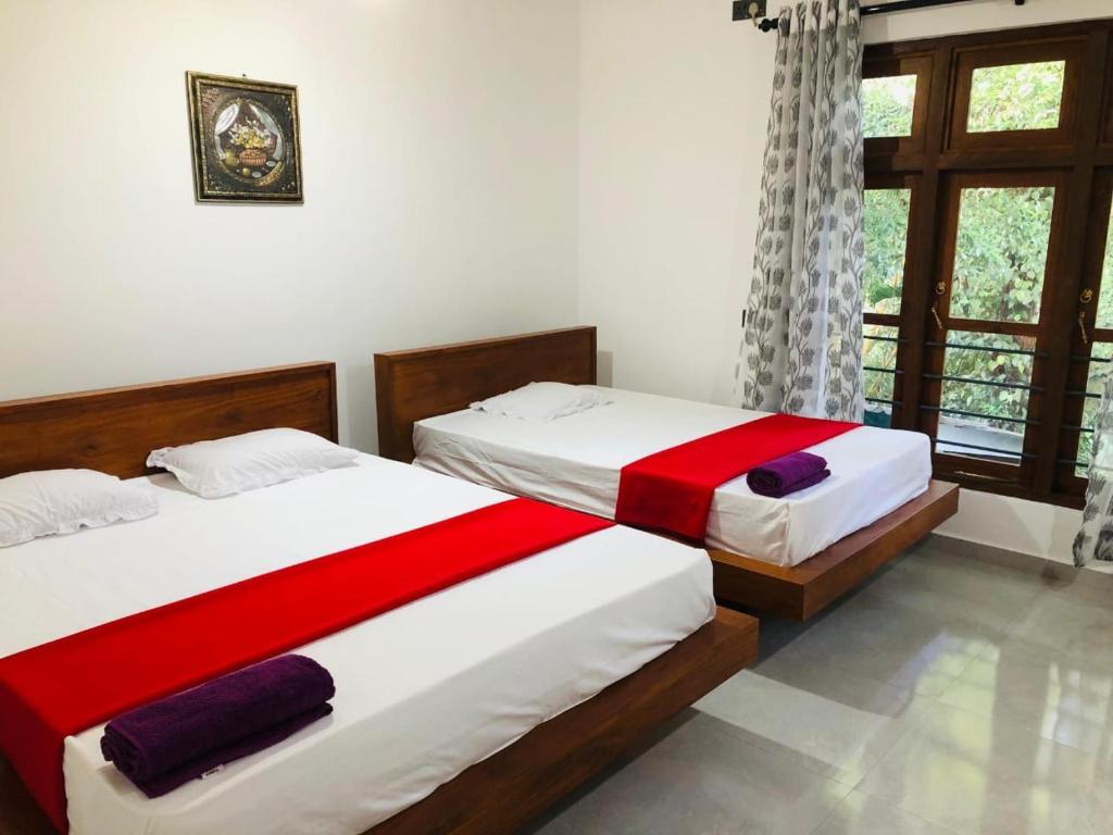 a bedroom with two beds and a window at Sinharaja Cottage in Nelluwa