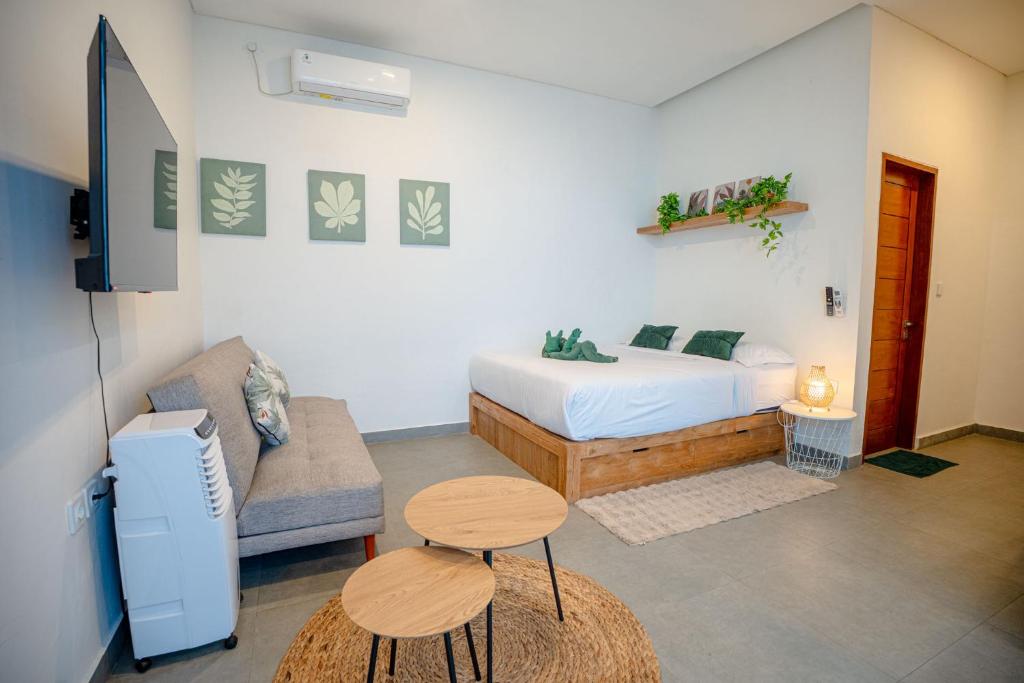 a bedroom with a bed and a couch and a table at Bali Bay by Urban Haven in Sanur