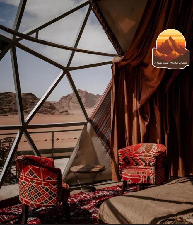 Habitación con 2 sillas, 1 cama y ventana en Wadi Rum Santa Camp, en Wadi Rum