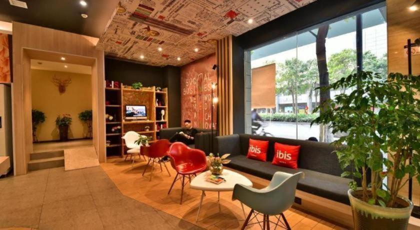 a lobby with a couch and chairs and a person sitting in a room at Ibis Xiamen Railway Station Hotel in Xiamen