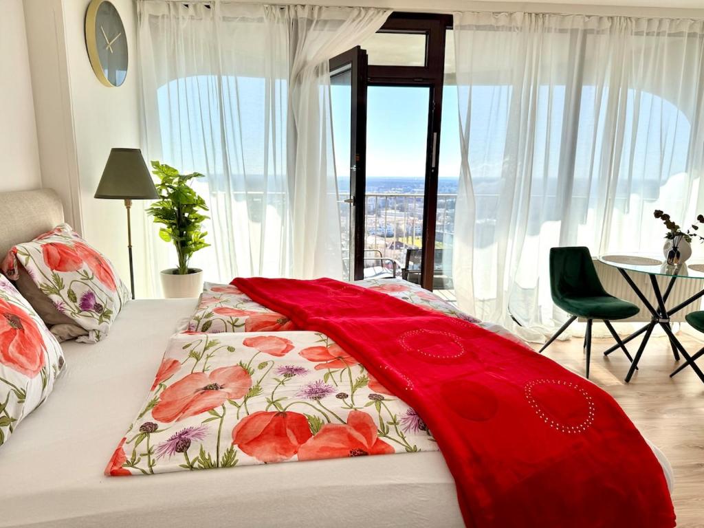 een slaapkamer met een bed met een rode deken erop bij Charmantes Appartement im 25 OG mit Aussicht und 60 Zoll TV in Augsburg