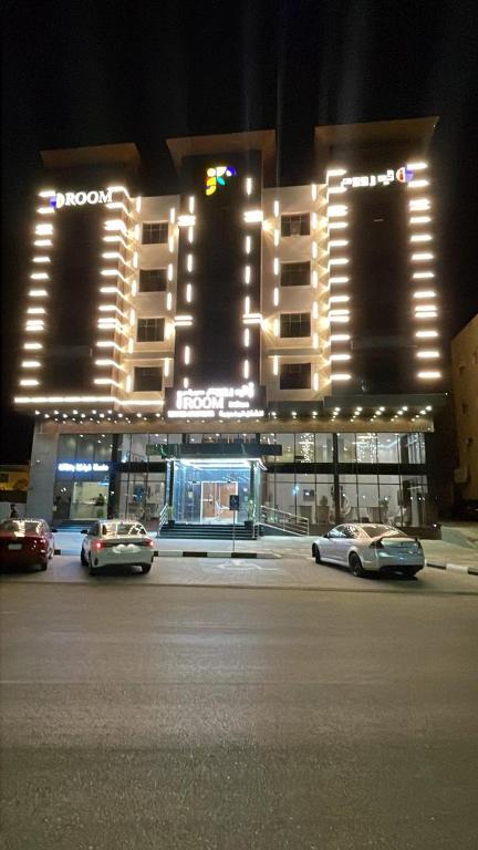two cars parked in front of a building at night at أي رووم سويتس للشقق المخدومة in Sakakah
