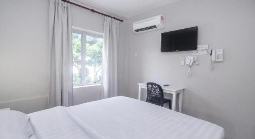 a bedroom with a bed and a desk and a window at OYO 90577 Safi Homestay in Kampong Tanjong Gelam