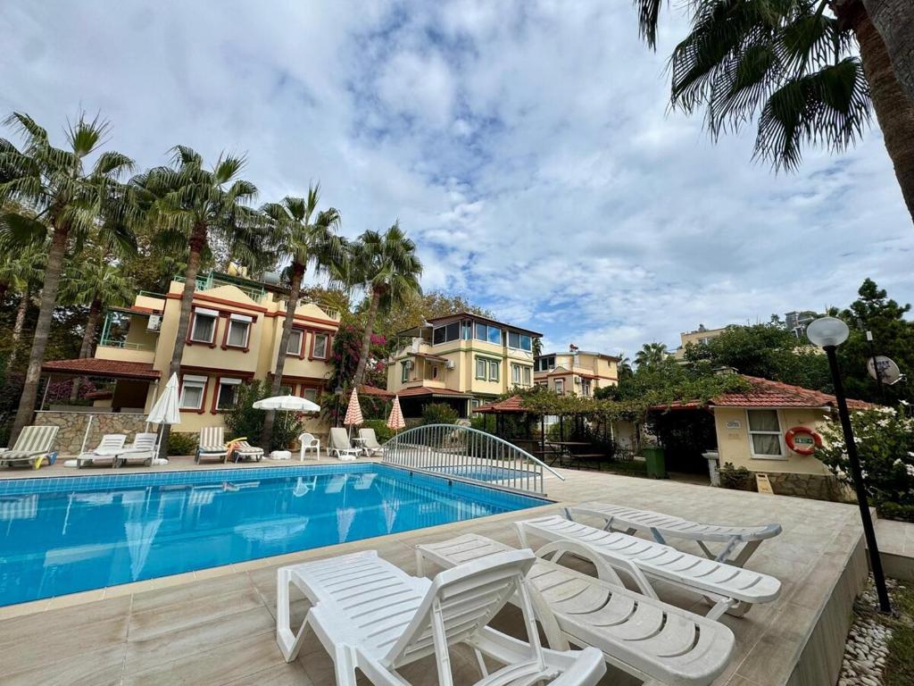 a swimming pool with white lounge chairs next to a house at Villa Konakli in Konaklı
