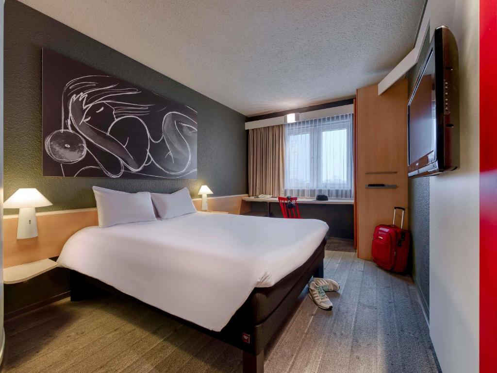 a bed in a room with a large white bed at ibis München Parkstadt Schwabing in Munich