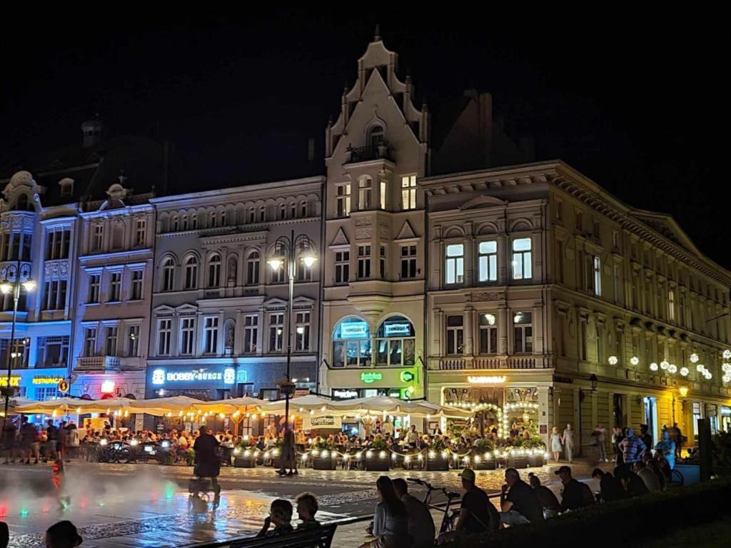 a group of people sitting in front of a building at night at Hej Bydgoszcz - Apartament XL na Starym Rynku in Bydgoszcz