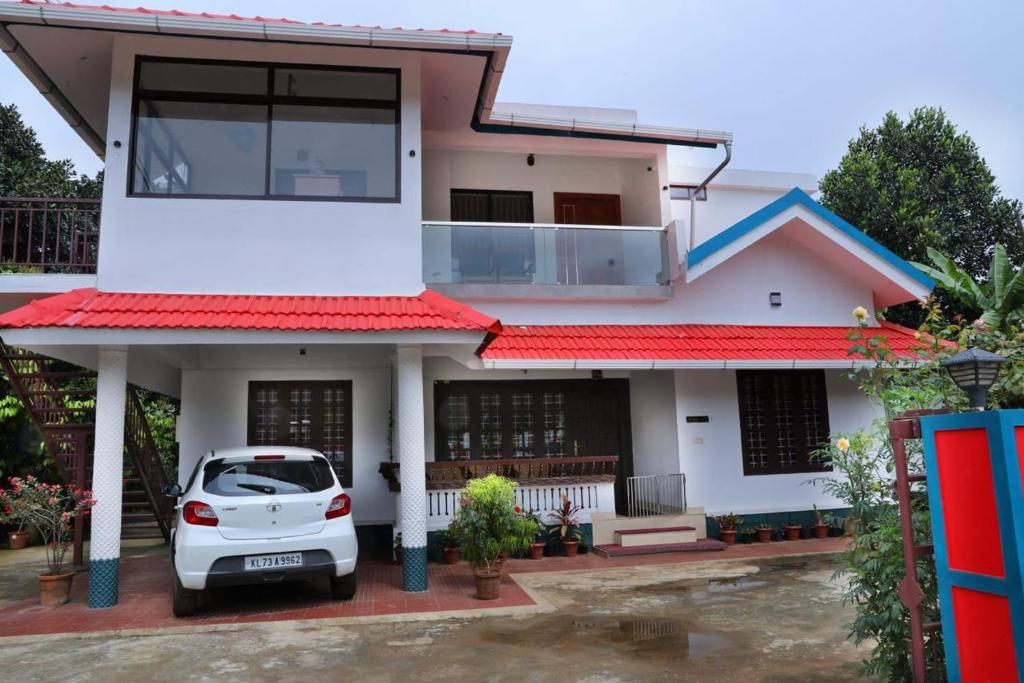 WayanadにあるJosebas Inn Vythiriの前に車が駐車されている白い家